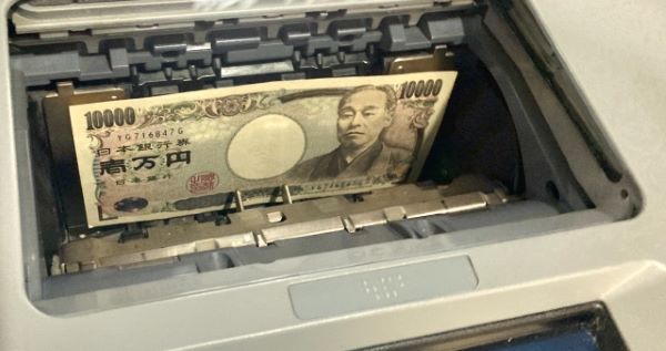現金自動預け払い機に入っている1万円札の画像